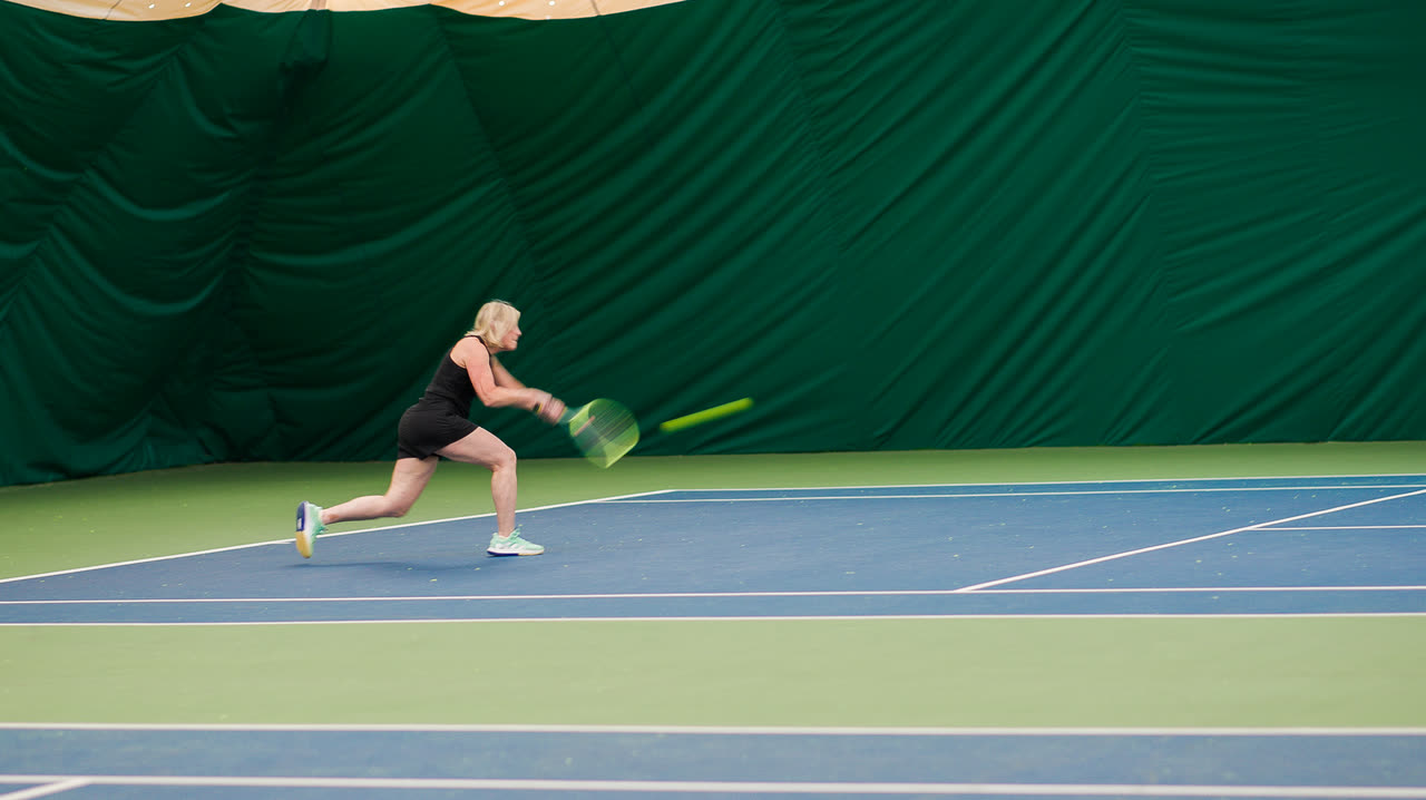 A player reaching for a backhand during an indoor pickleball rally at Match Point KC